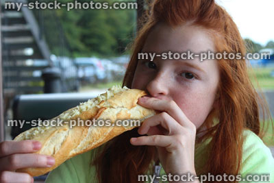 Stock image of girl eating cheese and pickle sandwich / baguette, cheese sub