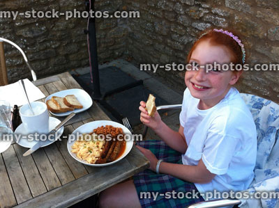 Stock image of girl eating fried breakfast outside, al fresco dining