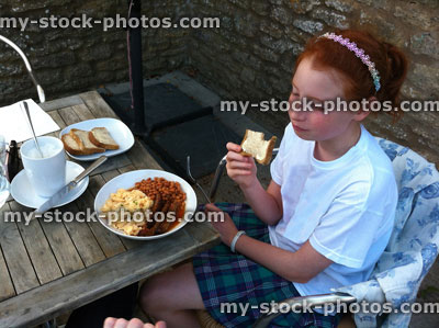 Stock image of girl eating fried breakfast outside, al fresco dining 