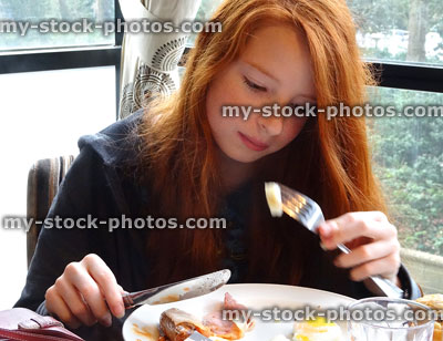 Stock image of girl eating full English fried breakfast / greasy fry up, bacon sausage, egg