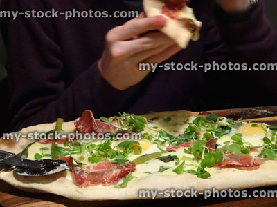 Stock image of rustic ham and egg pizza with spinach leaves