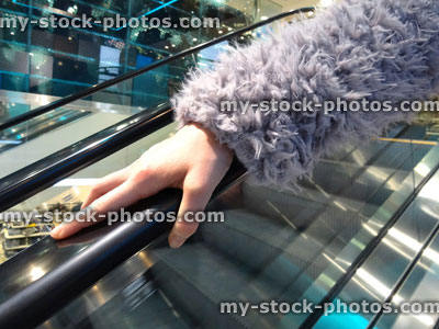 Stock image of girl's hand on escalator handrail / rail, germs, cold, flu virus, shopping mall