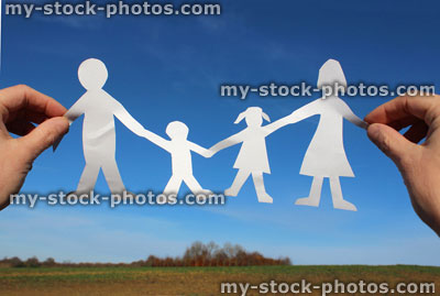 Stock image of family paper chain of people / dolls, held against blue sky