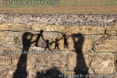 Stock image of family paper chain of people / dolls shadows / silhouettes against wall