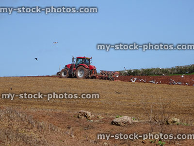 Stock image of tractor ploughing field in spring, digging in old crop