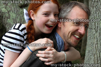 Stock image of laughing, happy father and daughter playing, having fun piggy back