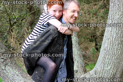 Stock image of laughing, happy father and daughter playing, having fun piggy back