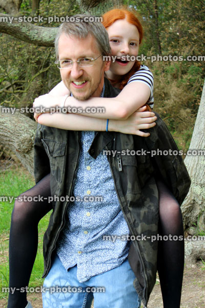 Stock image of father playing with daughter, having fun piggy back, carrying her