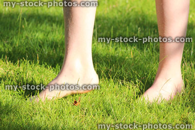 Stock image of girl walking barefoot on grass lawn, without shoes