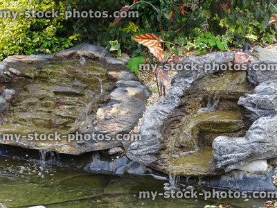 Stock image of fake plastic waterfalls with water cascading into pond