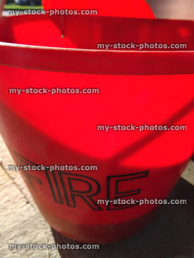 Stock image of red plastic fire bucket filled with sand, petrol / gas fuel filling station