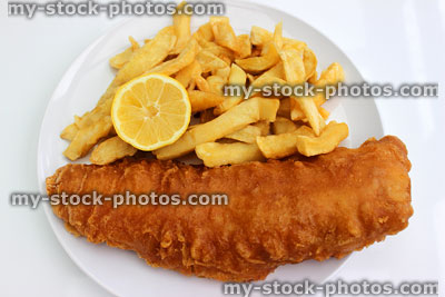 Stock image of battered fish and chips on a white plate with lemon