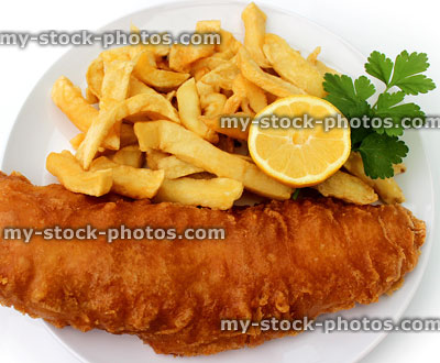 Stock image of battered cod, fish and chips on plate, lemon, parsley