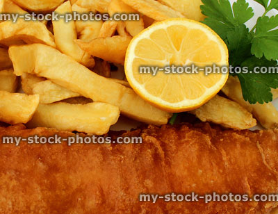 Stock image of battered fish and chips, slice of lemon, parsley