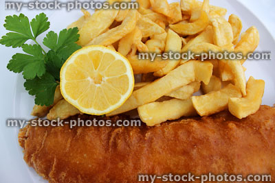 Stock image of fish and chips on white plate with lemon and parsley