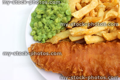 Stock image of battered fish and chips on white plate with mushy peas