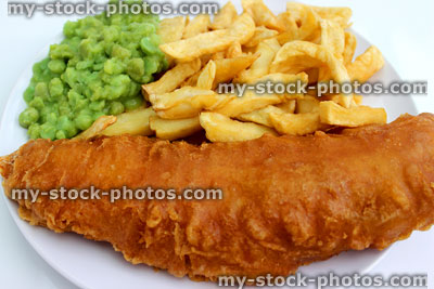 Stock image of battered fish and chips on white plate with mushy peas