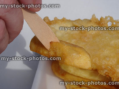 Stock image of eating battered fish / cod and chips with wooden fork