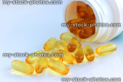Stock image of open, white plastic pill bottle of vitamin supplements (close up)