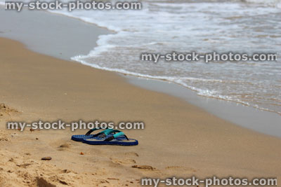 Stock image of flip flops / thongs on sand at seaside, beach sandals