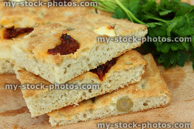 Stock image of homemade Italian focaccia bread slices, with olives, herbs