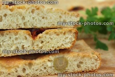 Stock image of slices of homemade focaccia bread showing texture, olives