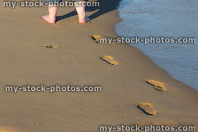 Stock image of footprints in sand by sea, beach footprints, barefoot girl / legs
