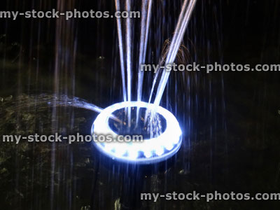 Stock image of illuminated, uplit pond fountain with bright white light
