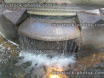 Stock image of contemporary fountain water feature, granite waterfall, splashing water, underwater lights