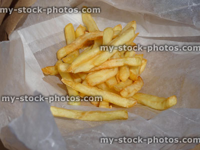 Stock image of crunchy French fries / chips on takeaway greaseproof paper