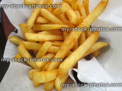 Stock image of cruchy French fries on paper, takeaway chips / junk food