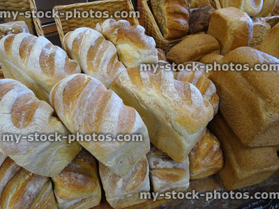 Stock image of homemade artisan bread loaves piled in bakery shop