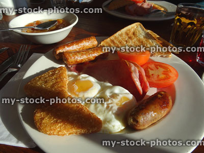 Stock image of fry-up / fried breakfast with sausages, fried-eggs, bacon, hash-browns