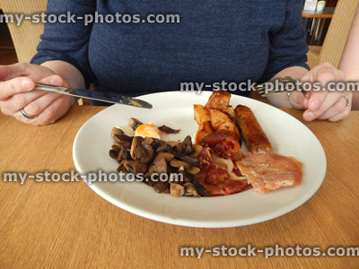Stock image of girl eating full English breakfast / fry up in 'greasy spoon' cafe