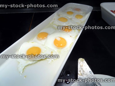 Stock image of greasy fried eggs platter, unhealthy full English breakfast buffet
