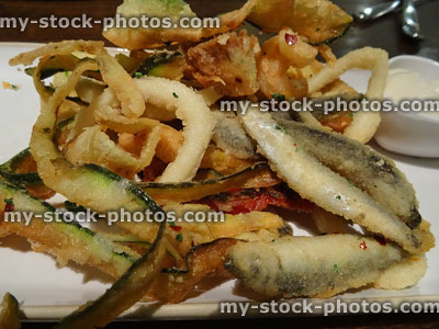 Stock image of fried fish platter with battered calamari rings, whitebait