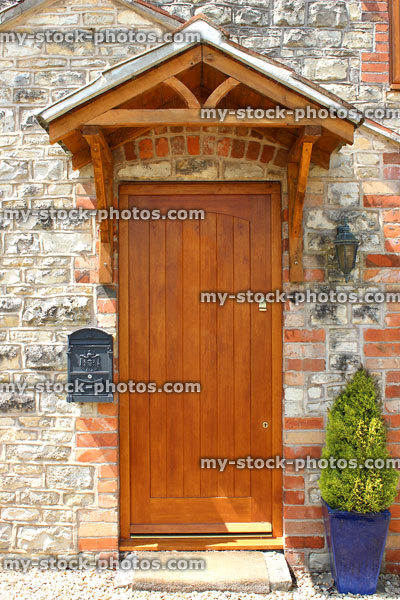 Stock image of wooden front door with porch, stone wall, cottage