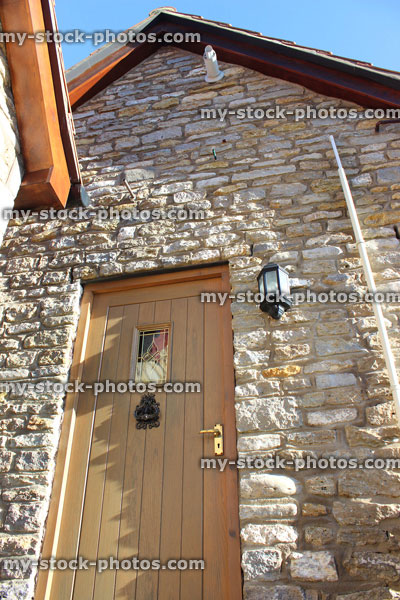 Stock image of wooden front door / back door knocker, cobblestone wall