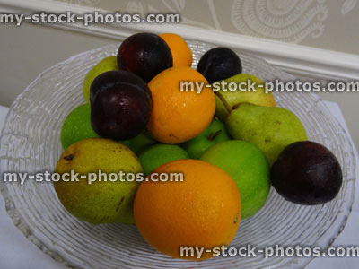 Stock image of glass fruit bowl, washed apples, pears, oranges, plums