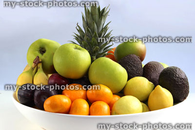Stock image of fruit bowl, with pineapple, apples, bananas, satsumas, oranges, lemons, avocados