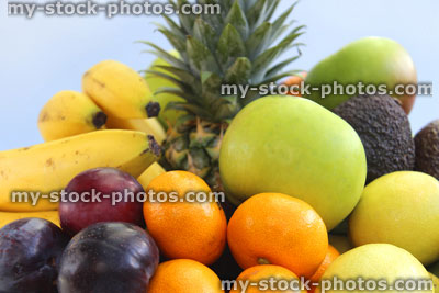 Stock image of fruit bowl, with pineapple, apples, bananas, satsumas, oranges, lemons, avocados