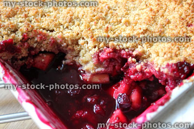 Stock image of homemade summer fruit crumble with apple, blackberries, raspberries, blueberries, cherries
