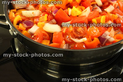 Stock image of tomatoes, onions and peppers, vegetables cooking in frying pan
