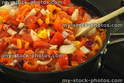 Stock image of wooden spoon stirring vegetables cooking in non stick frying pan