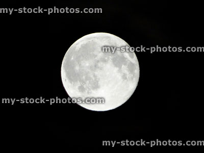 Stock image of full moon shining in black, night time sky without stars