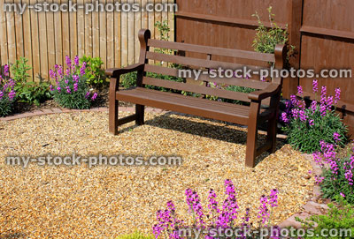 Stock image of wooden garden bench surrounded by Erysimum 'Bowles's Mauve'