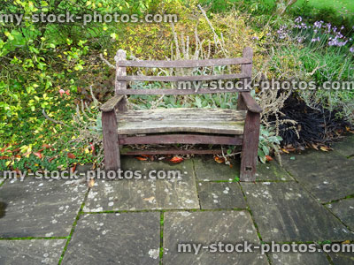 Stock image of irregular grey flagstone paving / rectangular pattern, wooden garden bench