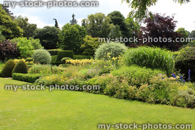 Stock image of green garden lawn, shrubs and herbaceous border flowers