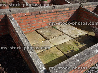 Stock image of red brick coldframe in vegetable garden, paving slab base