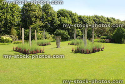 Stock image of formal garden, green lawn with flower borders, berberis, stone columns